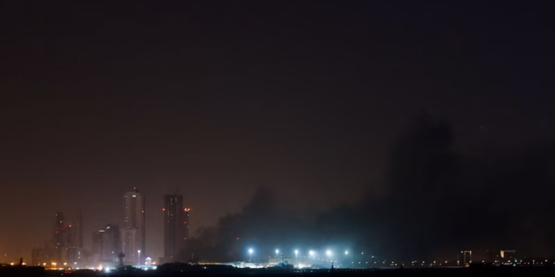 Smoke rising over a city skyline at night following missile or drone strikes