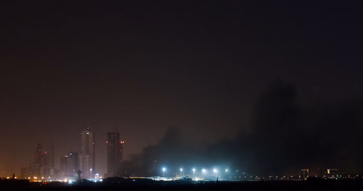 Smoke rising over a city skyline at night following missile or drone strikes